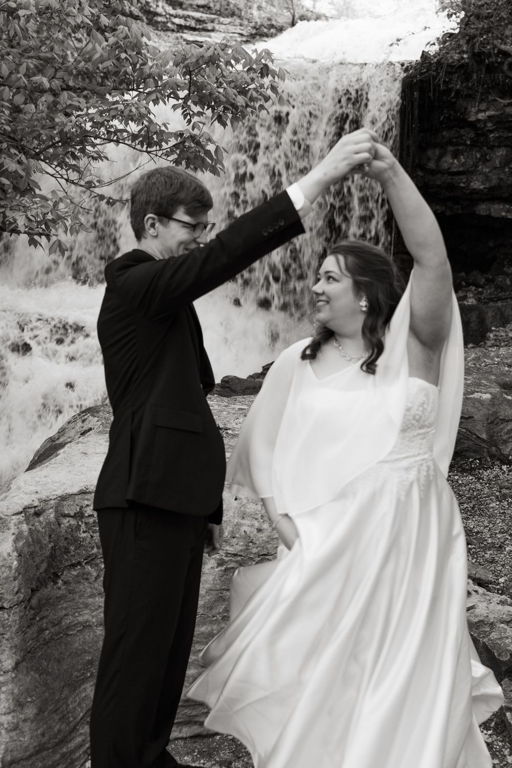 ©AnnaVonRiesenPhotography Bridal Portraits | B&W image of a couple smiling at each other with a waterfall in the background.