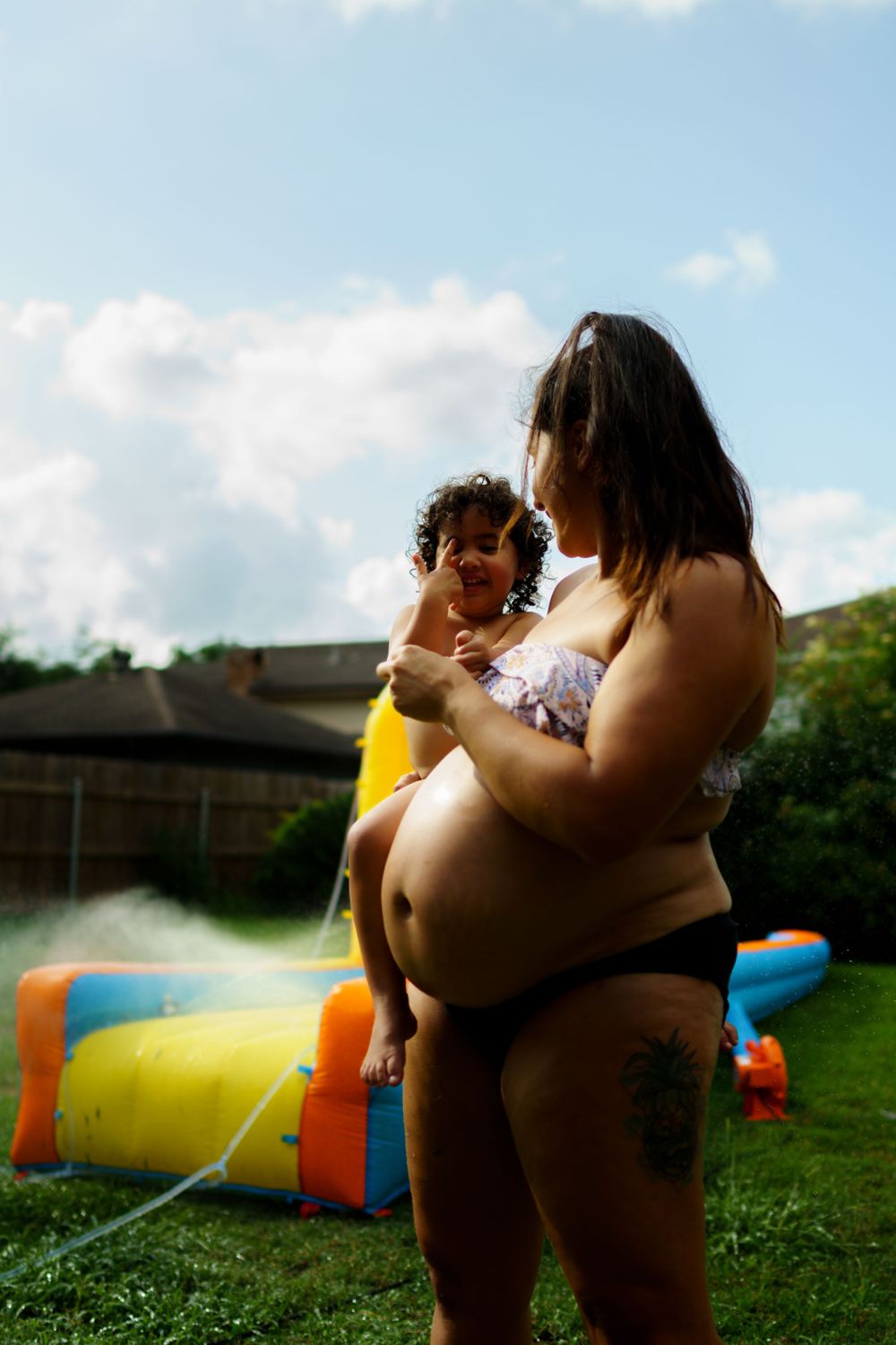 Summer backyard scene with an inflatable pool and water slide under blue skies.