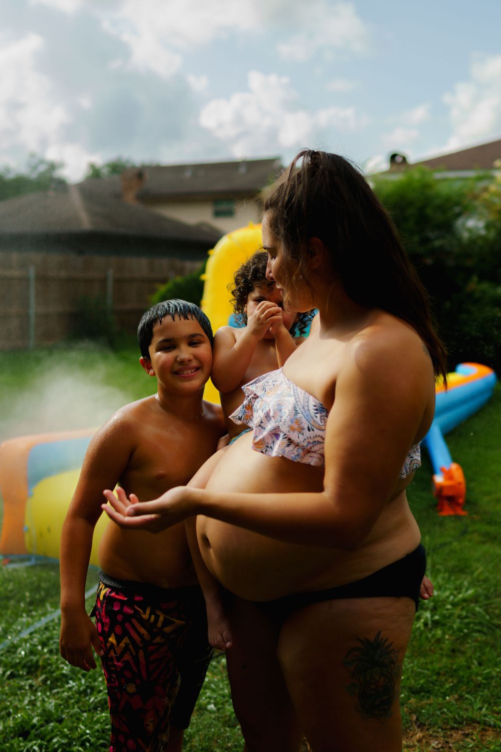People enjoying a summer gathering near an inflatable water slide in a backyard.