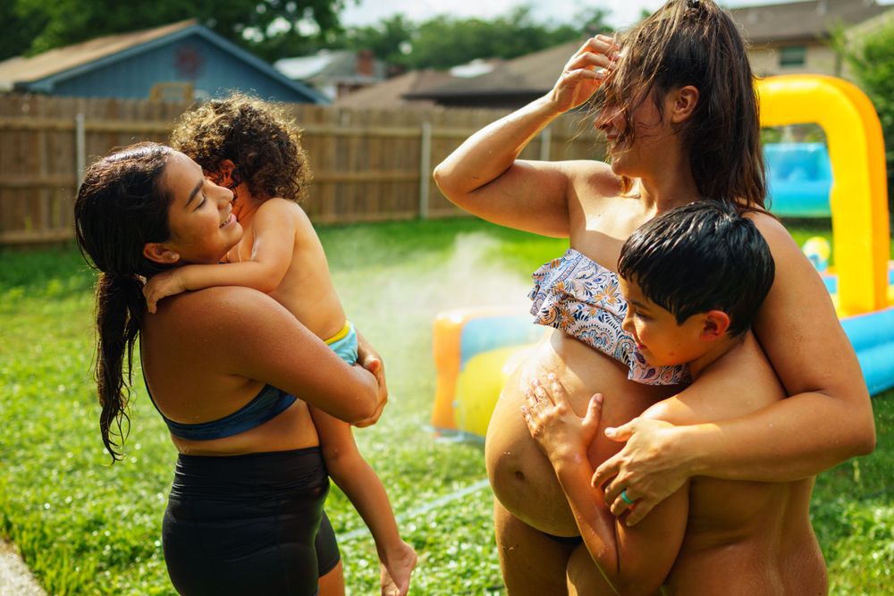 Joyful summer moment shared between loved ones in a backyard with a yellow inflatable pool visible.
