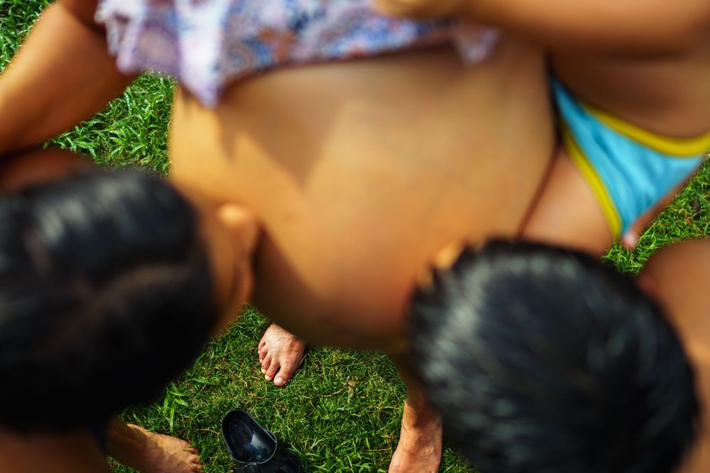 Close-up view of people gathered together on green grass during a summer day.