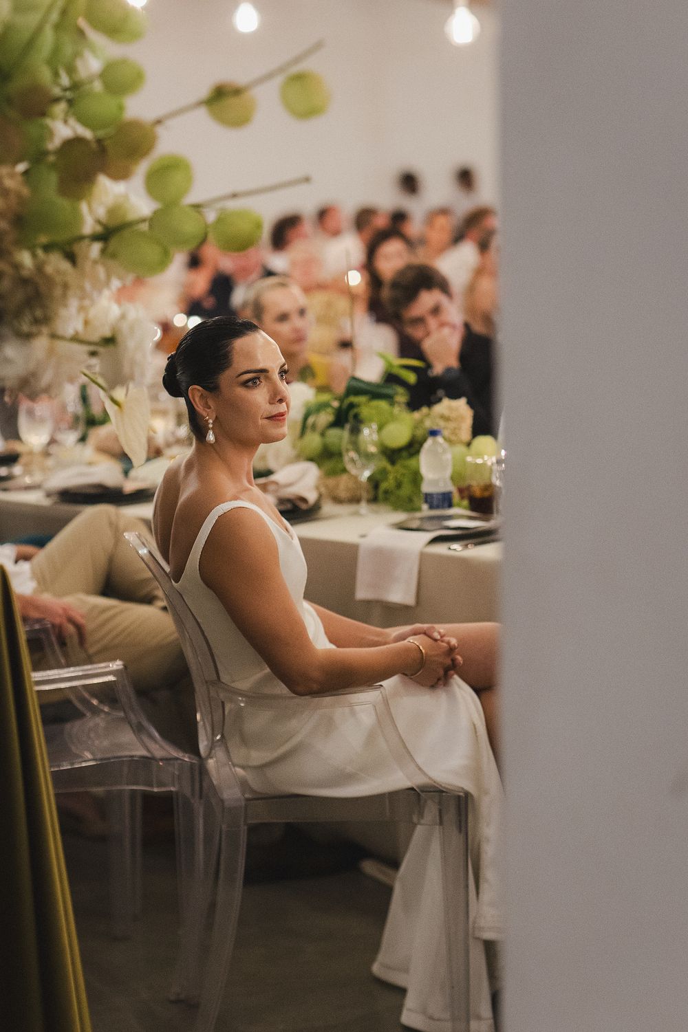 Bride seated at beautifully styled reception during wedding speeches