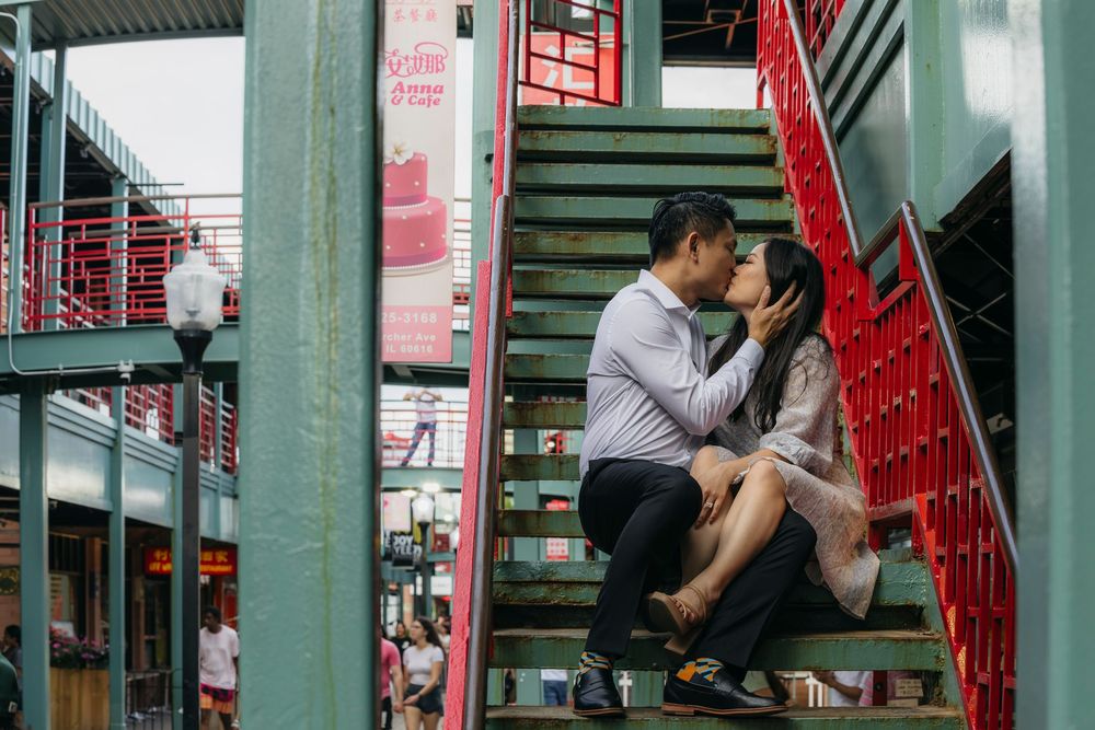 Couple sharing a romantic kiss on colorful green and red stairs in Chinatown Chicago during engagement session