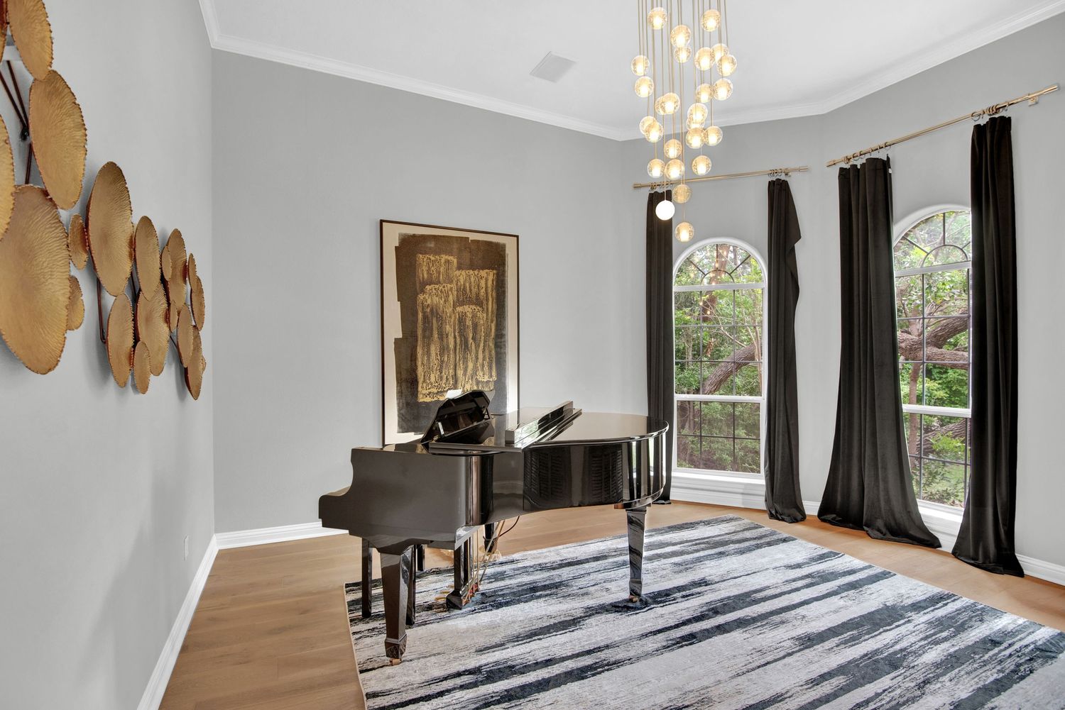 Elegant music room with baby grand piano, modern chandelier, and tall windows with dark curtains.