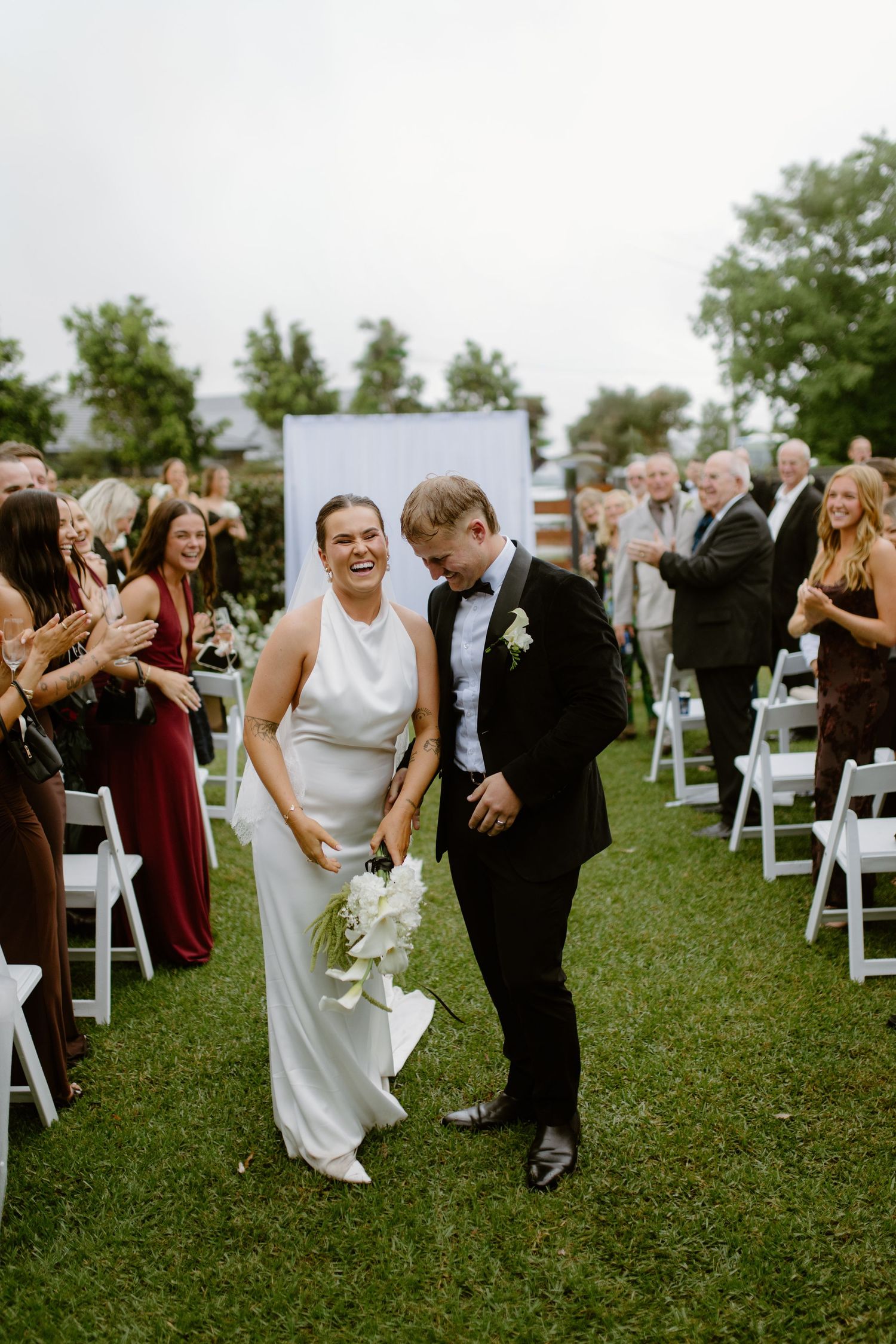 Bride and groom share a romantic moment bathed in golden sunlight, nearly kissing in wedding attire.