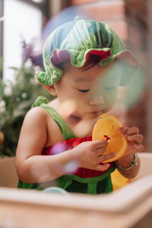 A sequence of photos shows someone in a green hairnet eating an orange fruit or citrus with enthusiasm.一組照片顯示，有人戴著綠色髮網，興致勃勃地吃著橘色水果或柑橘類水果。