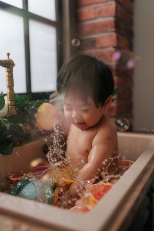 Sequence of photos showing a baby splashing and playing during bath time in a white tub.一組照片顯示，一名嬰兒在白色浴缸中洗澡時嬉戲玩耍。