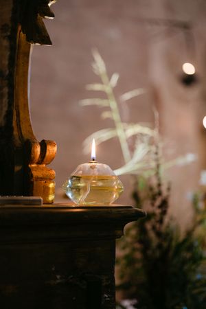 Lit crystal candle on rustic wooden surface with soft bokeh lights background.