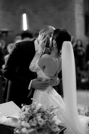 Bride and groom share their first kiss at the altar during a romantic black and white wedding ceremony.