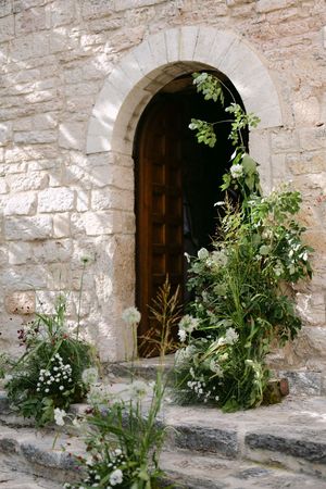 Stone church entrance decorated with lush wildflower and greenery floral arrangements.