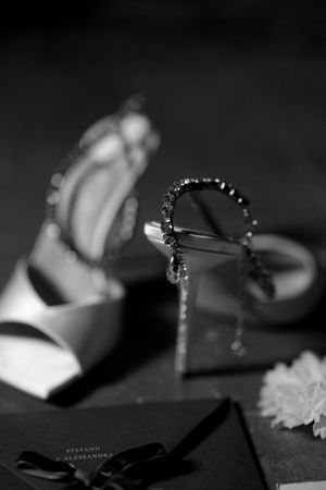 Black and white photo of bridal heels and crystal earrings with wedding stationery.