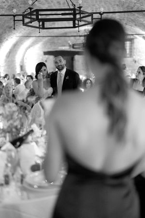 Black and white shot of bride and groom watching bridesmaid speech at reception.