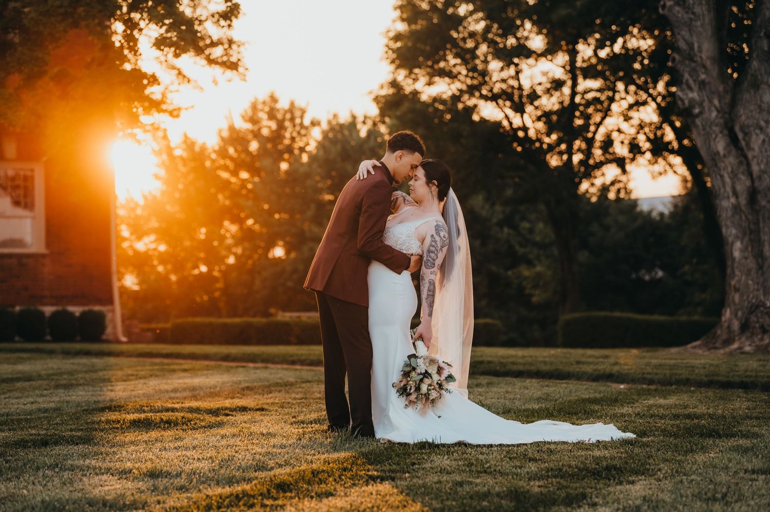 A romantic sunset wedding portrait with golden light streaming through trees.