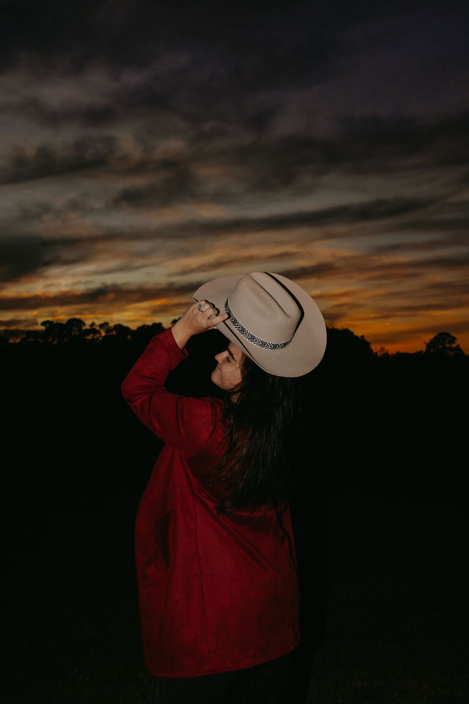 Close-up view of a cowboy hat brim against a sunset sky.