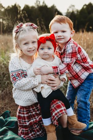 siblings Christmas blonde hair red hair baby with red bow field
