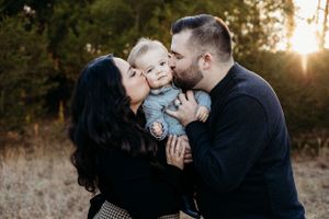 mom dad and baby kissing baby cheek