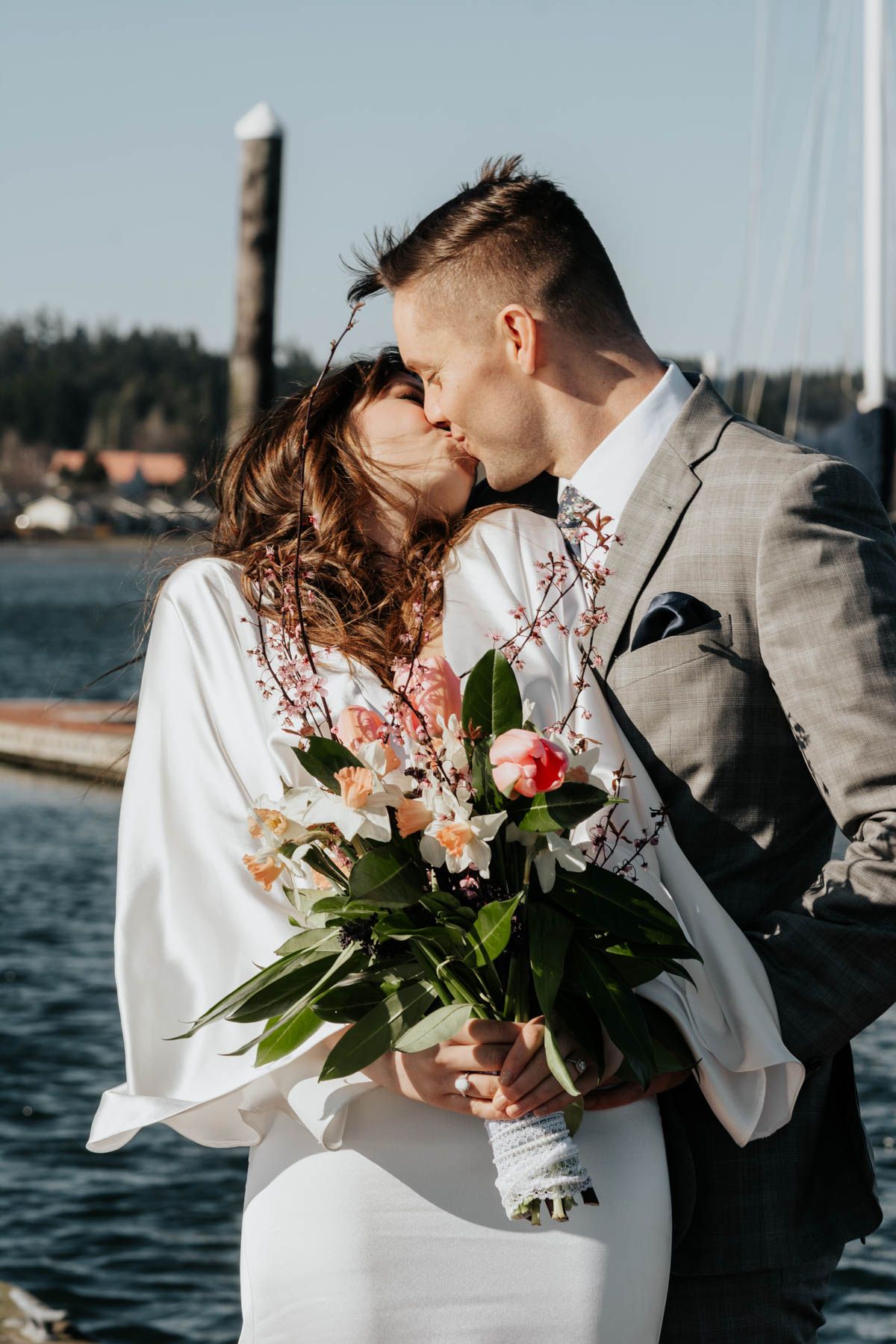 Romantic waterfront wedding photos featuring a beautiful bouquet of pink and white flowers.