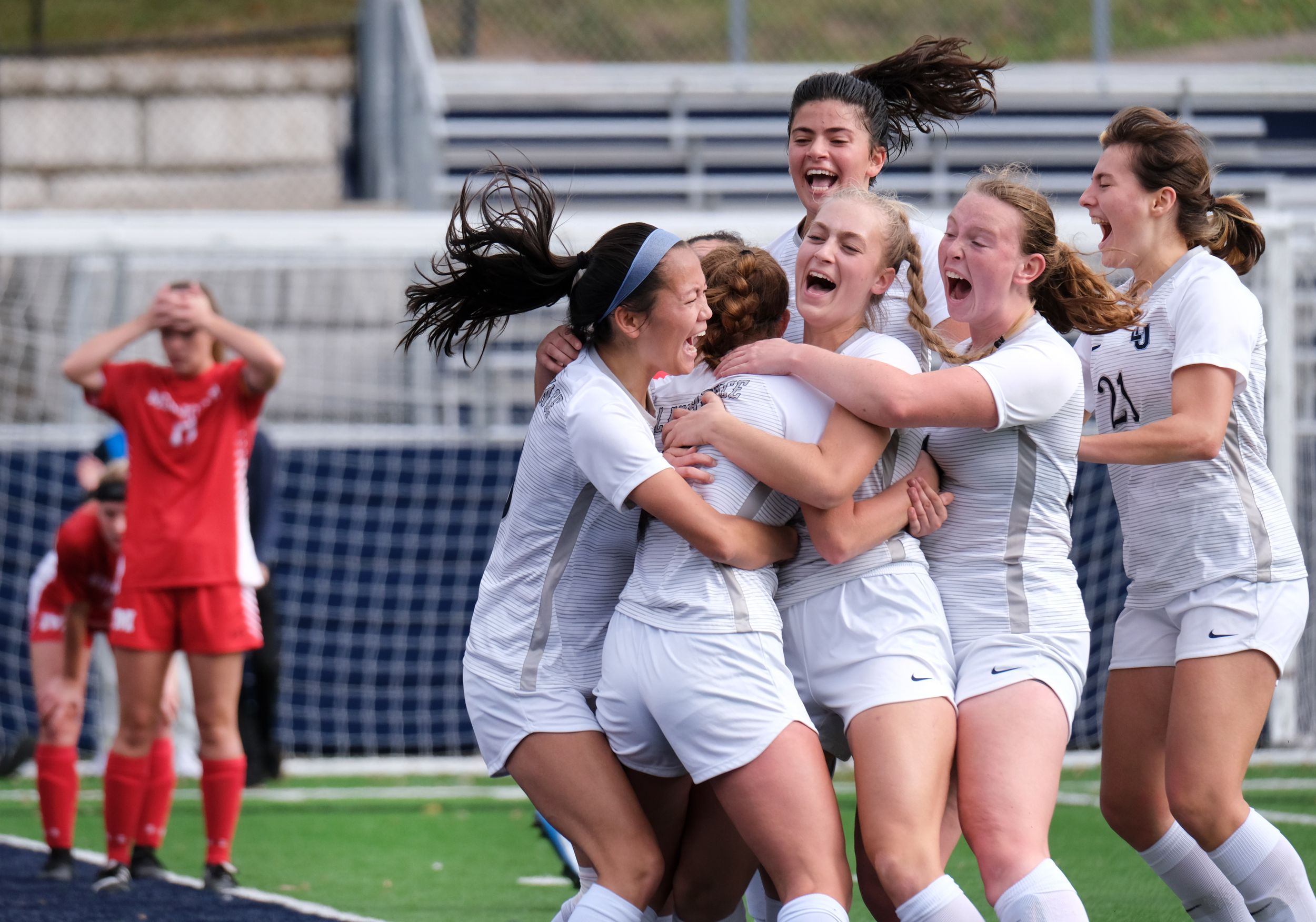 A group of women's soccer players jump in celebration after a win.