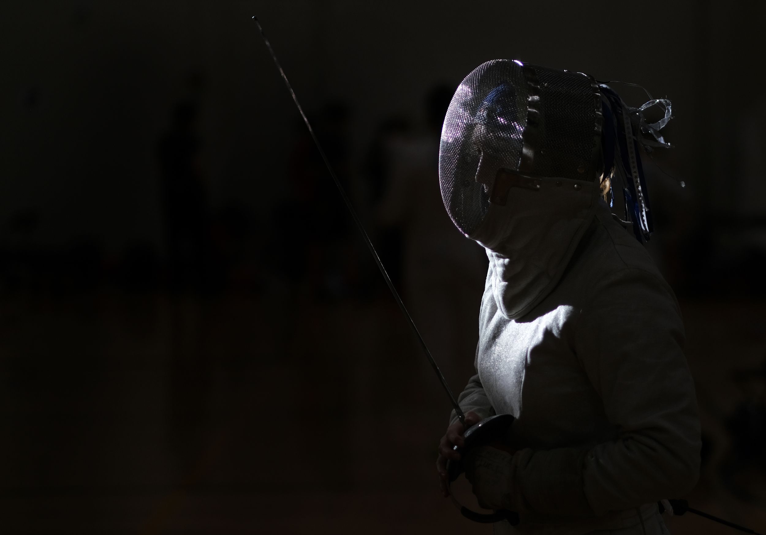 A beam of light is cast on a fencer about to compete in a bout.