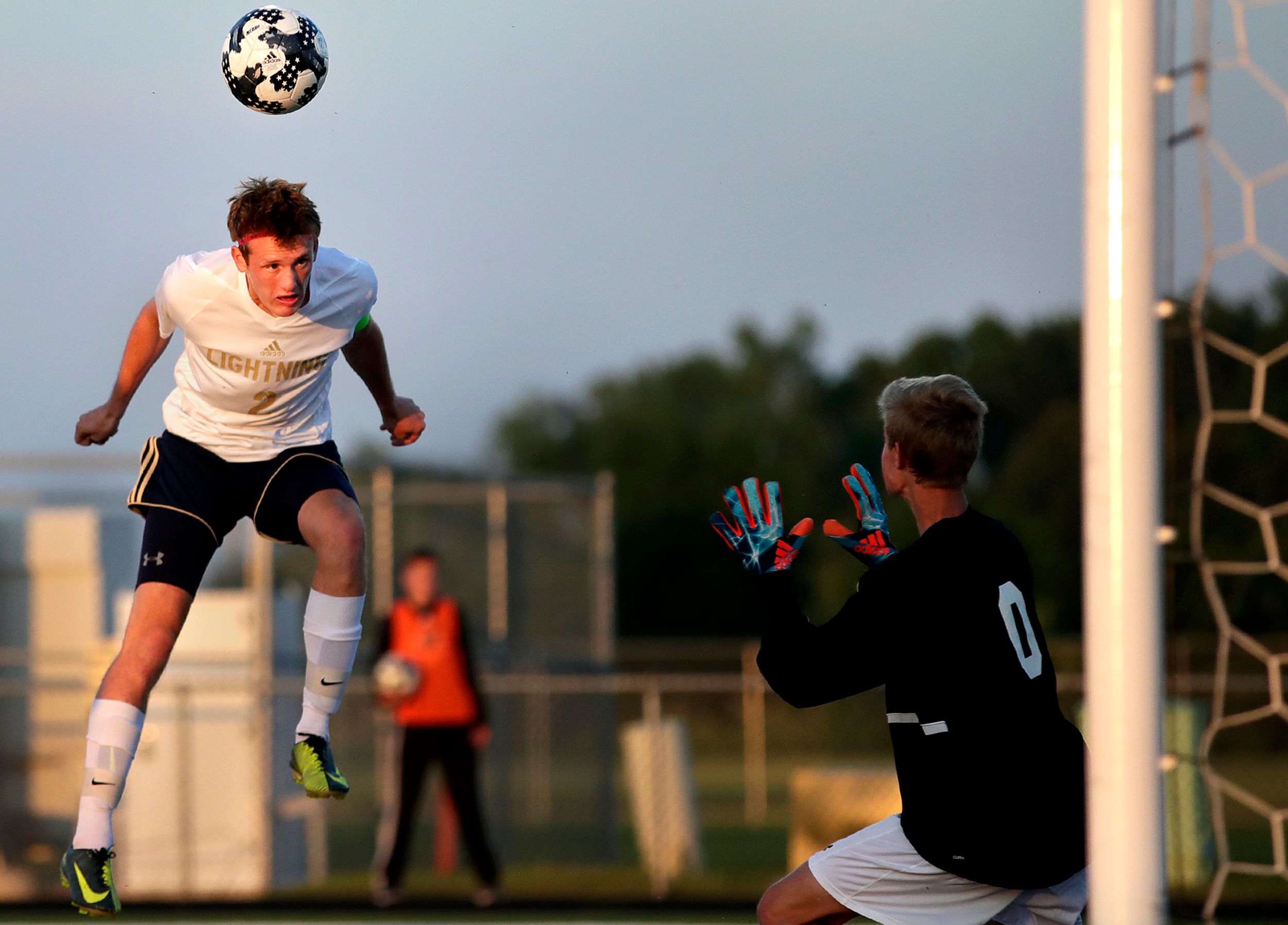 A soccer player heads the ball toward goal.