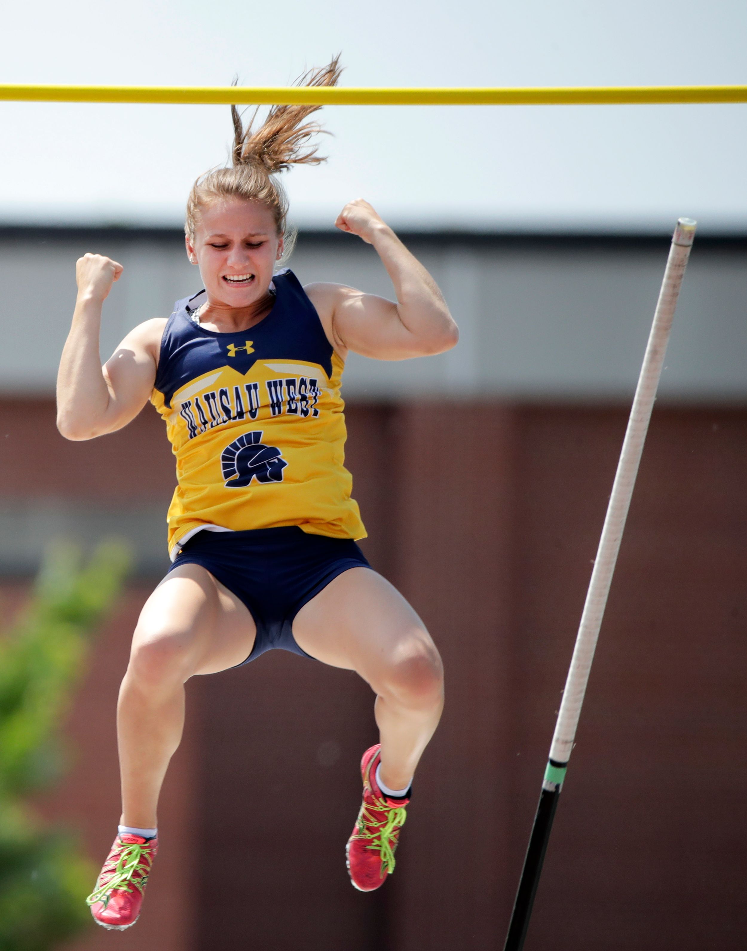 A pole vaulter celebrates after clearing the bar.