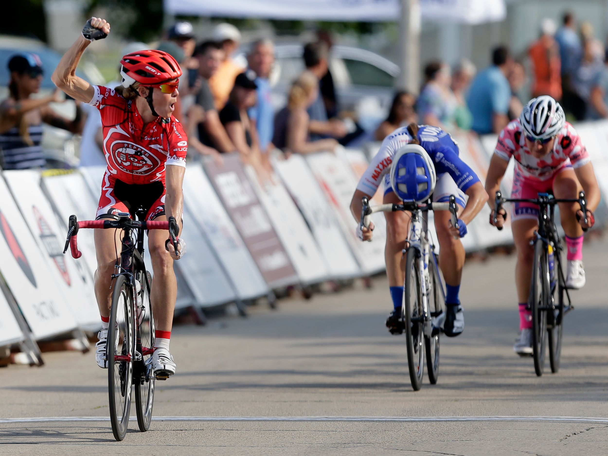 A cyclist celebrates a win as she crosses the finish line.