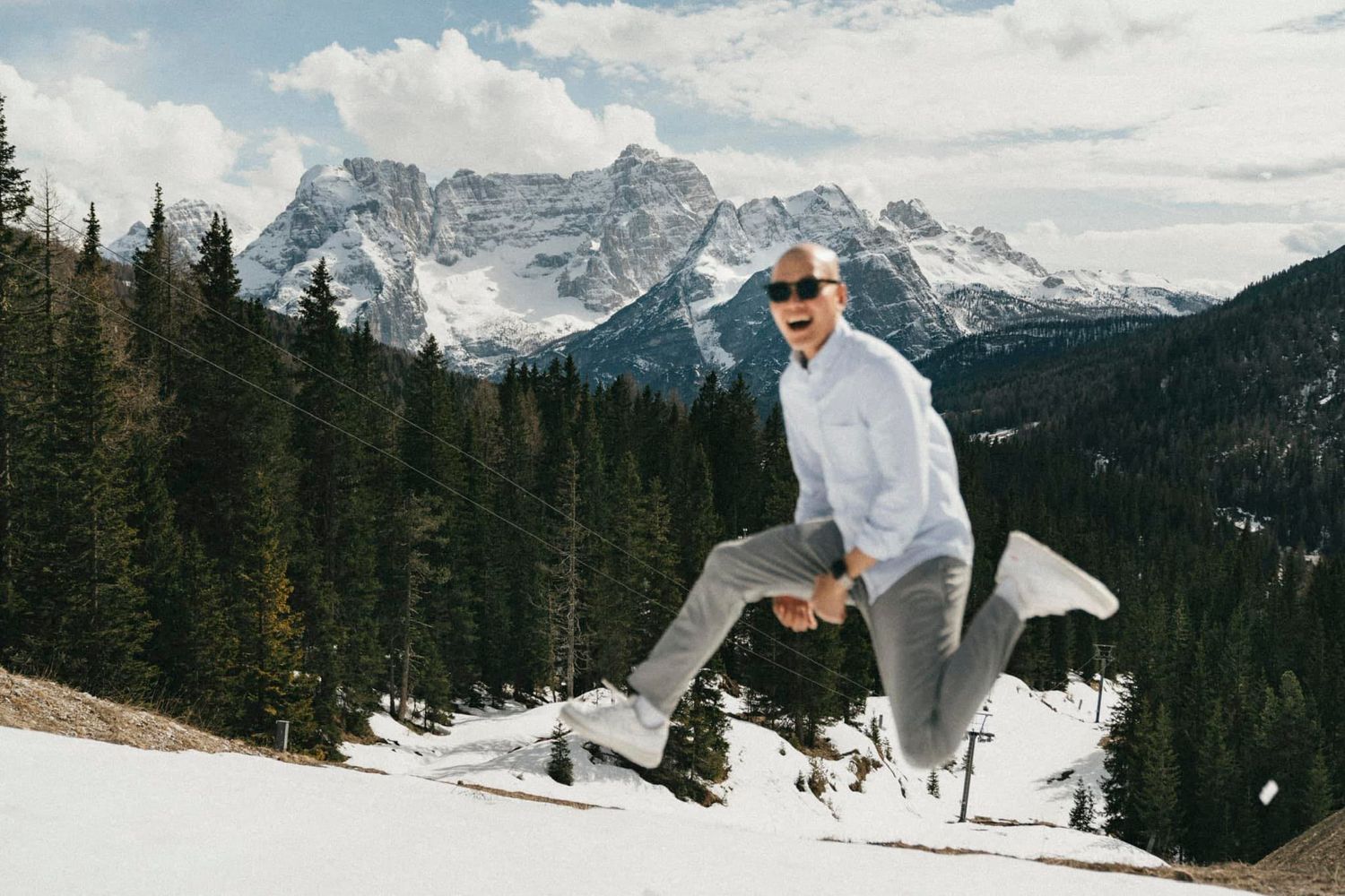Playful winter scene of skier jumping in snow with mountain backdrop.