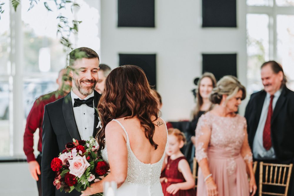 Wedding ceremony moment in bright modern venue with burgundy and blush color scheme.