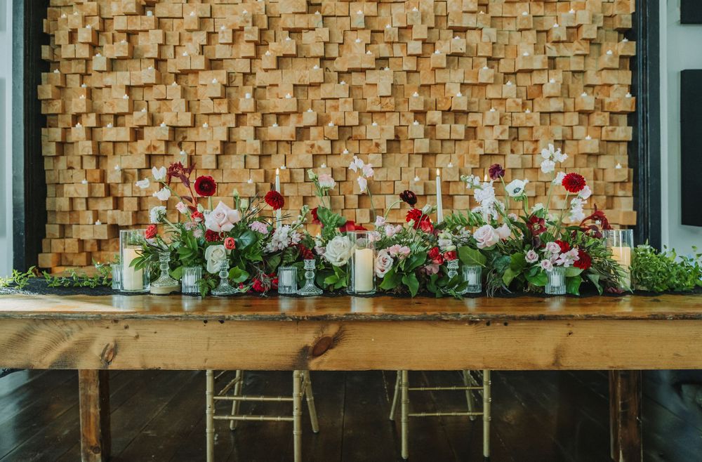 Row of delicate floral arrangements displayed on wooden shelf against textured wall.