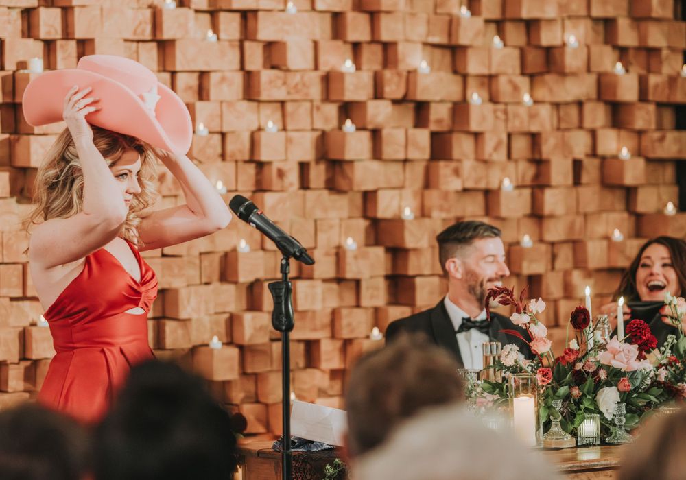 Wedding reception speech delivered at table with decorative textured wall backdrop.