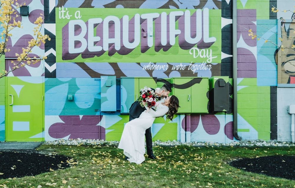 Romantic wedding photo against a colorful street art wall with 'Beautiful' text.