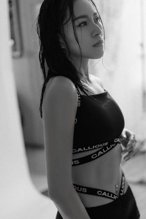 Black and white photo of a young woman with wet hair wearing a Callious crop top and high-waisted bottoms.