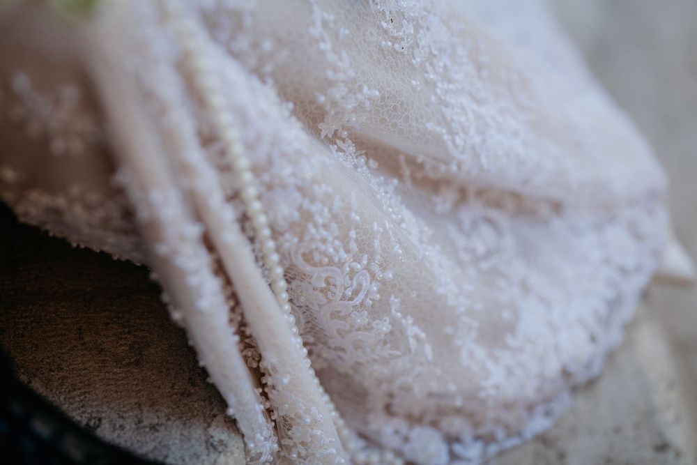 Close-up detail of intricate beaded lace fabric on a bridal wedding gown.