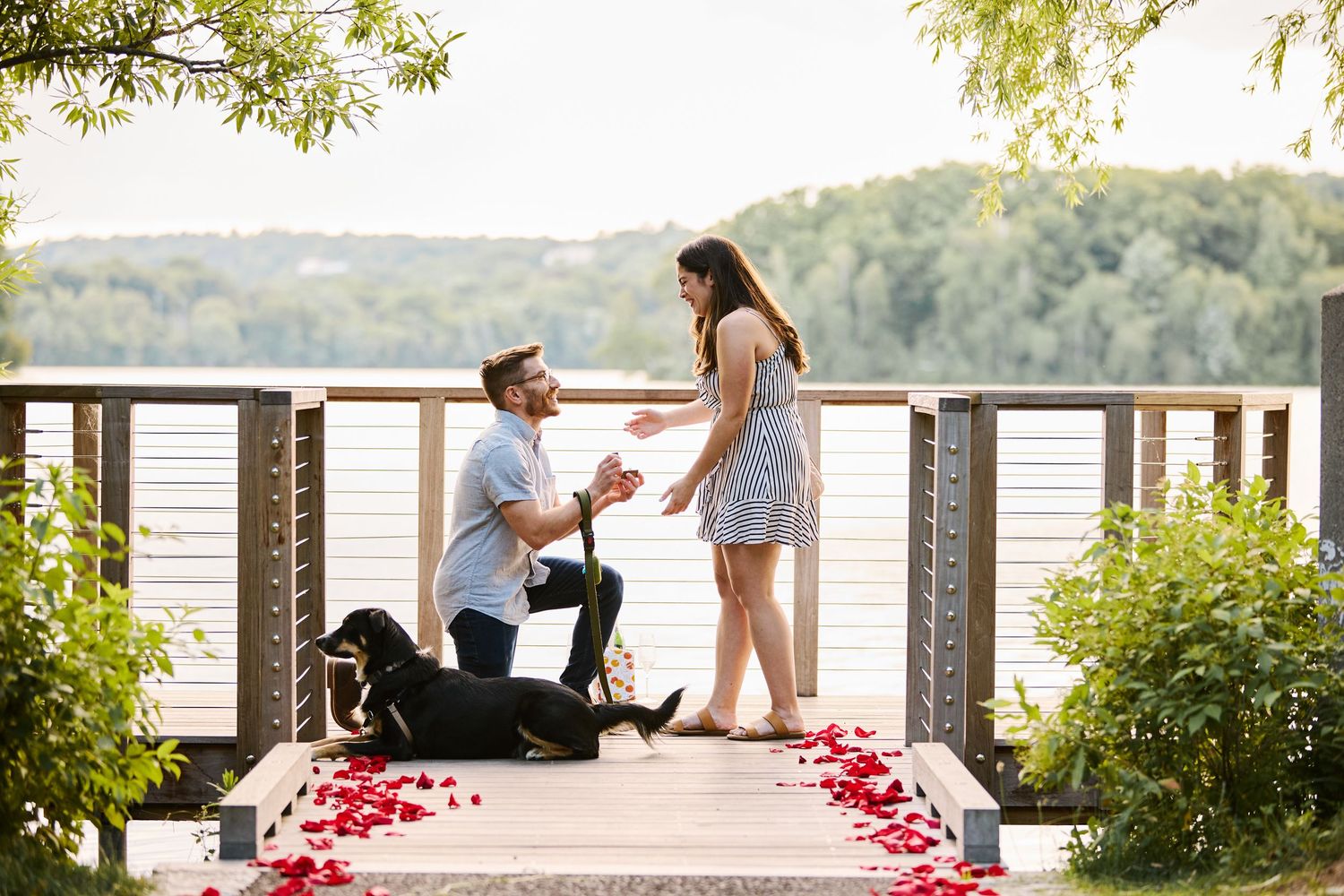 A casual black and white portrait of a couple sharing a joyful moment on a porch of a lakehouse.