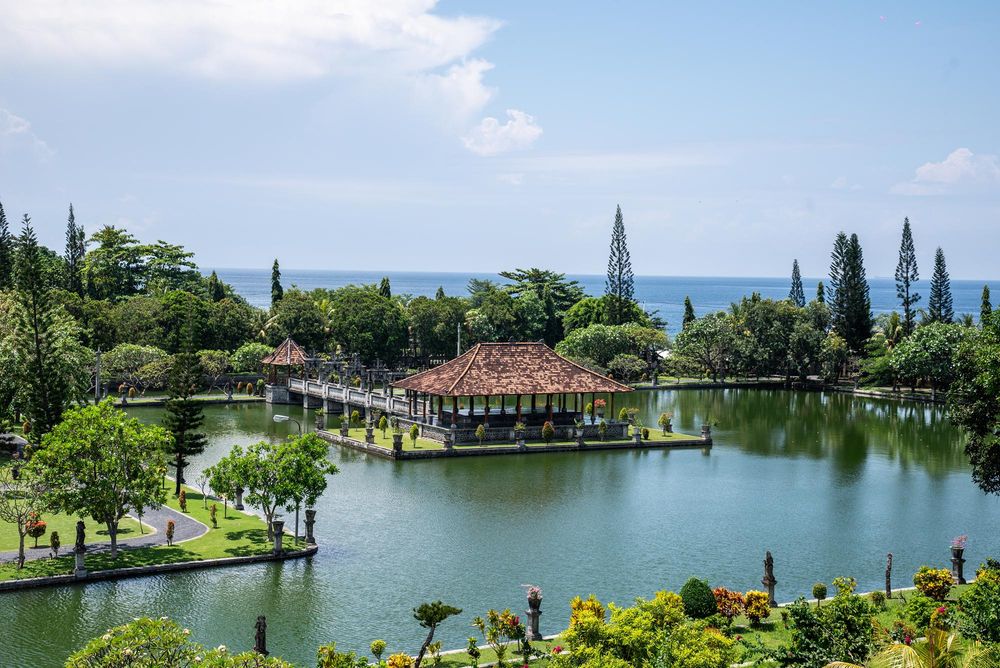 Aerial view of Tirta Gangga water palace in Bali with ornate pavilions surrounded by serene ponds and lush tropical gardens.