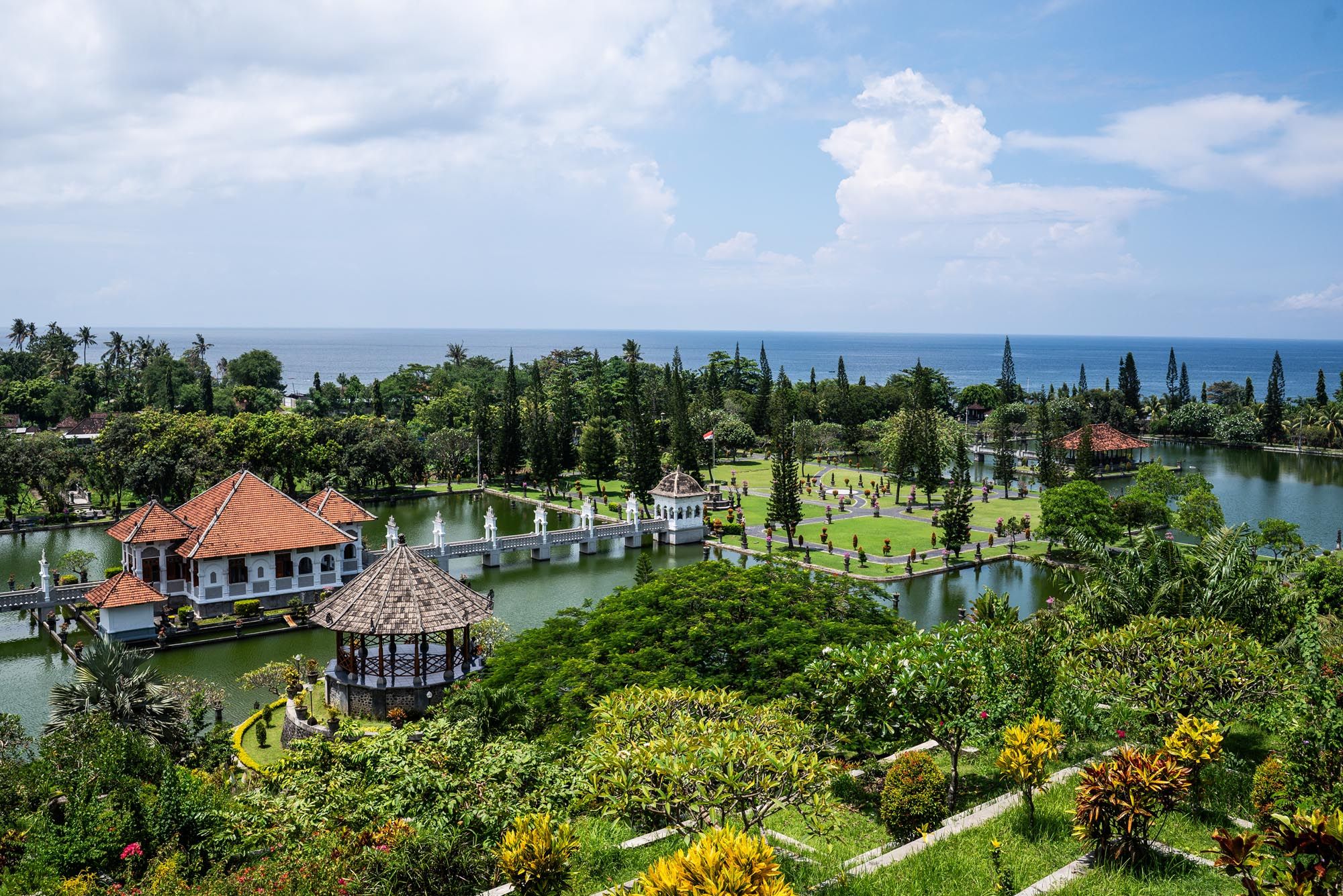 Panoramic view of Taman Ujung royal water palace in Bali surrounded by lush gardens and ocean views.