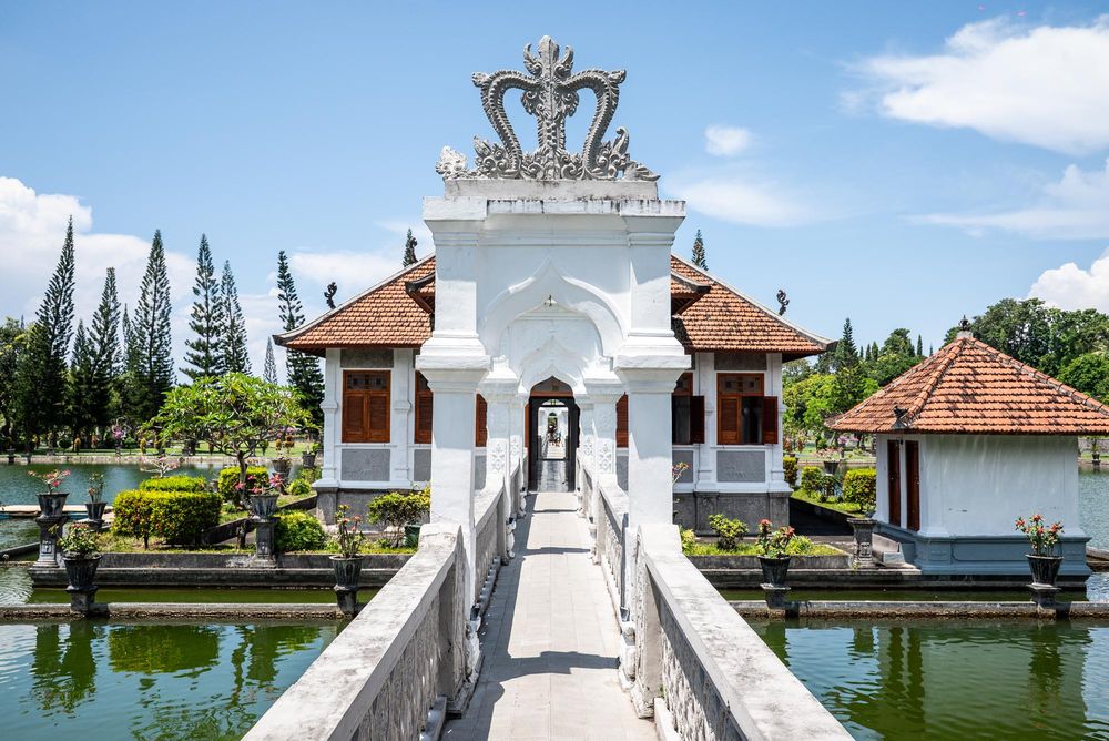 Ornate white gateway bridge over a serene pond at Taman Ujung Water Palace in Bali, Indonesia.
