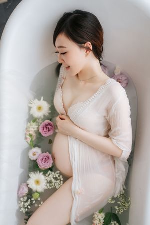 Maternity photoshoot featuring soft pink dress and delicate floral arrangements with daisies and lavender roses孕婦寫真，以柔和的粉紅色連身裙和精緻的雛菊、薰衣草玫瑰花束