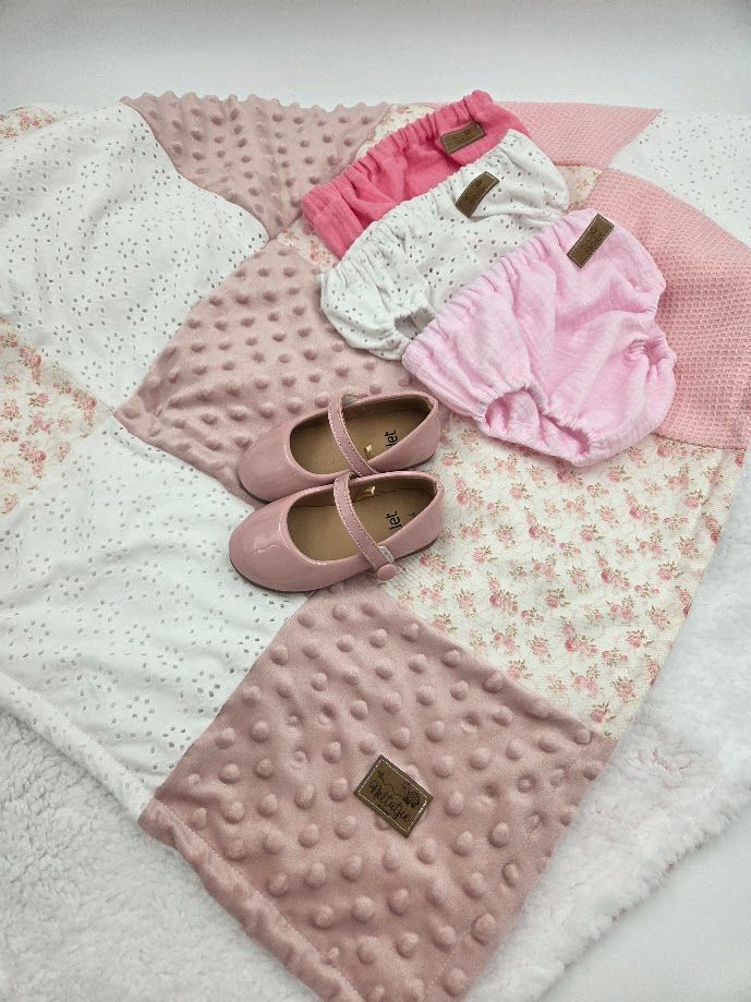 Pink baby girl set with patchwork blanket, Mary Jane shoes, ruffled socks, and bloomers in soft pink tones.