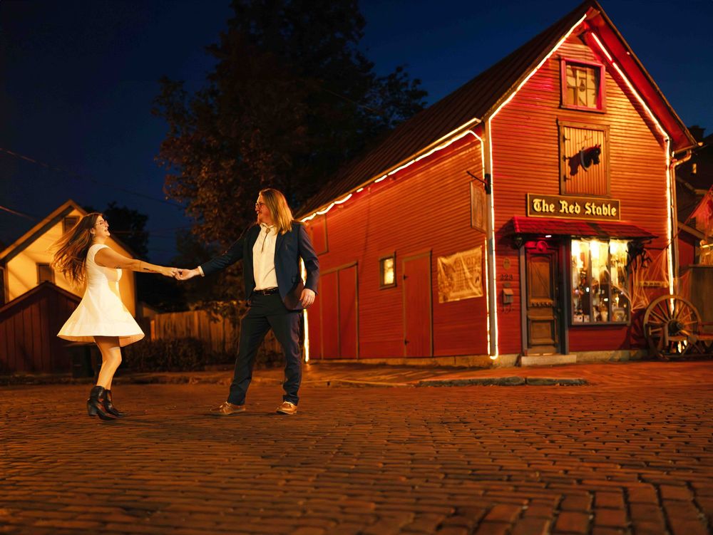 Couple dancing on cobblestone street at night outside The Red Stable, a charming red barn building lit warmly.