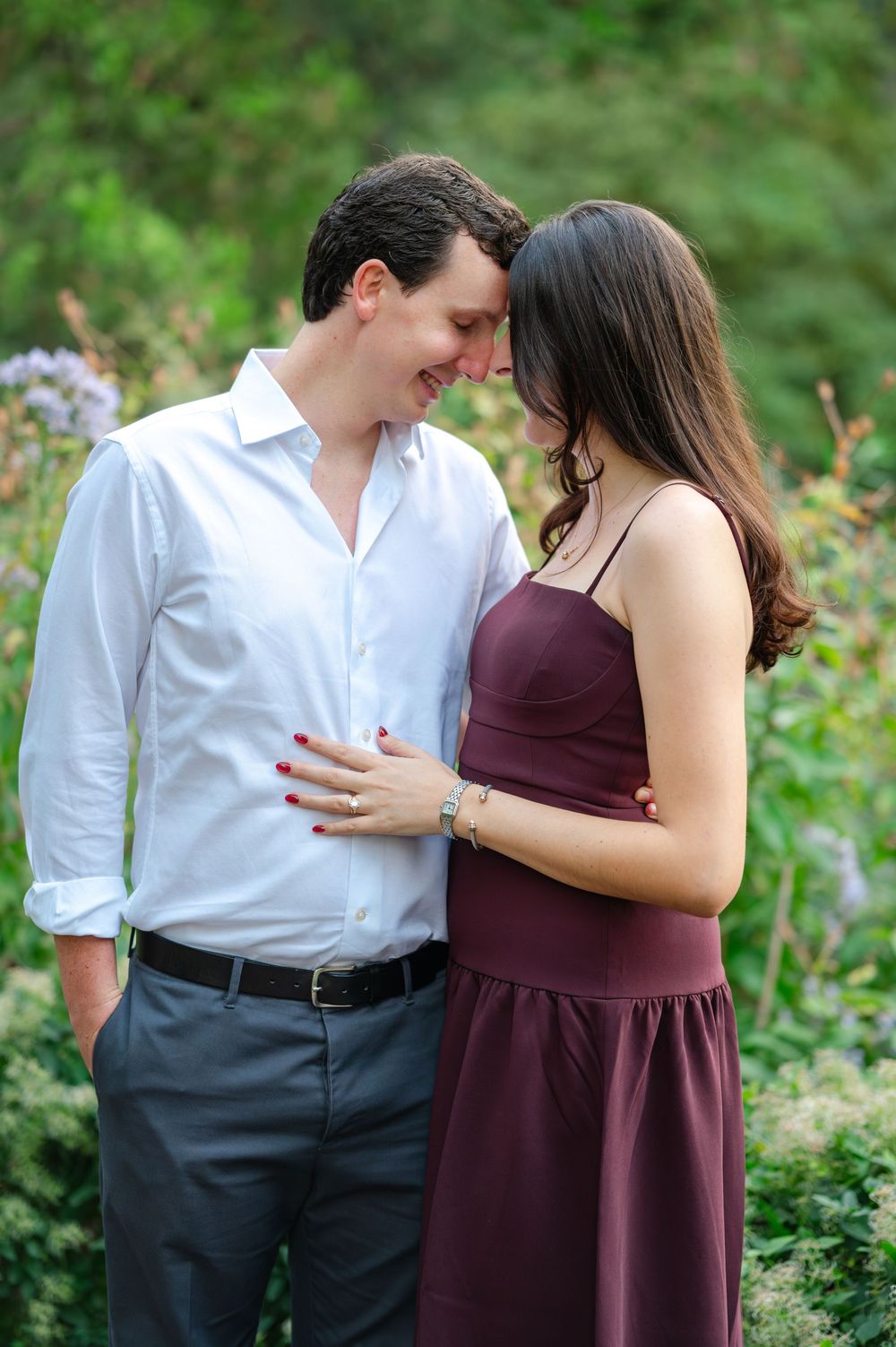 Happy couple shares an intimate forehead-to-forehead moment surrounded by wildflowers in a garden.
