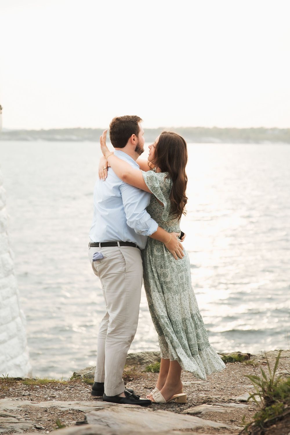 Couple embracing and kissing by the waterfront on rocky shore, Castle Hill.  Engagement photography Newport RI