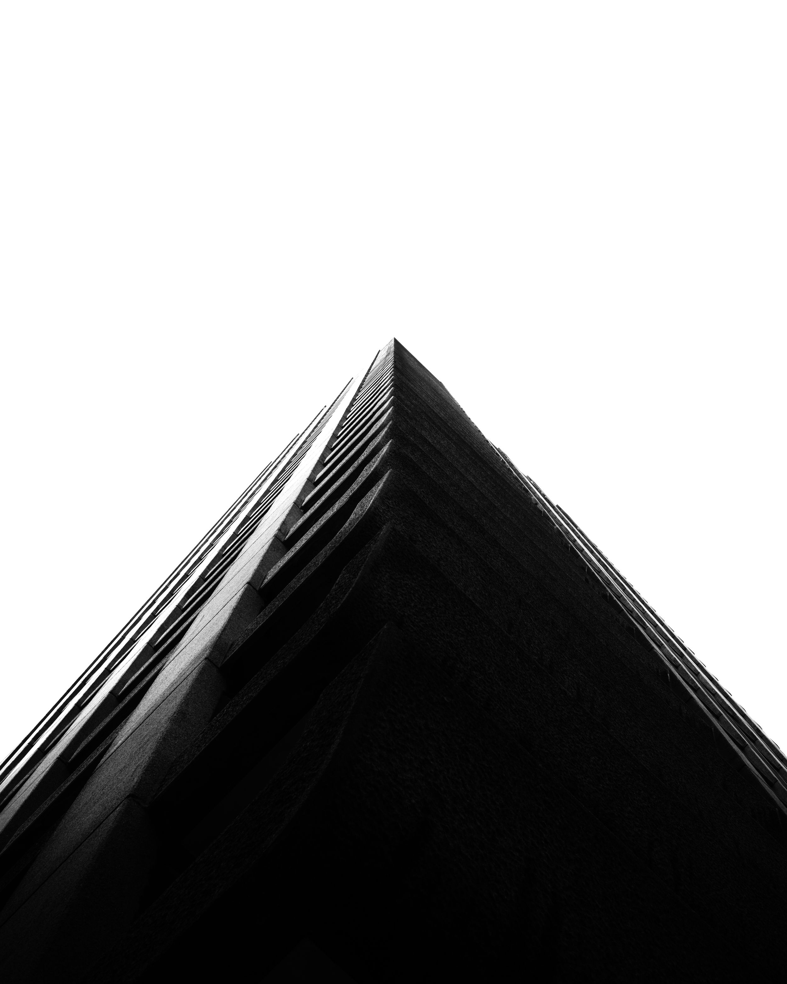 Black and white architectural photo of a pyramid-shaped building corner against the sky