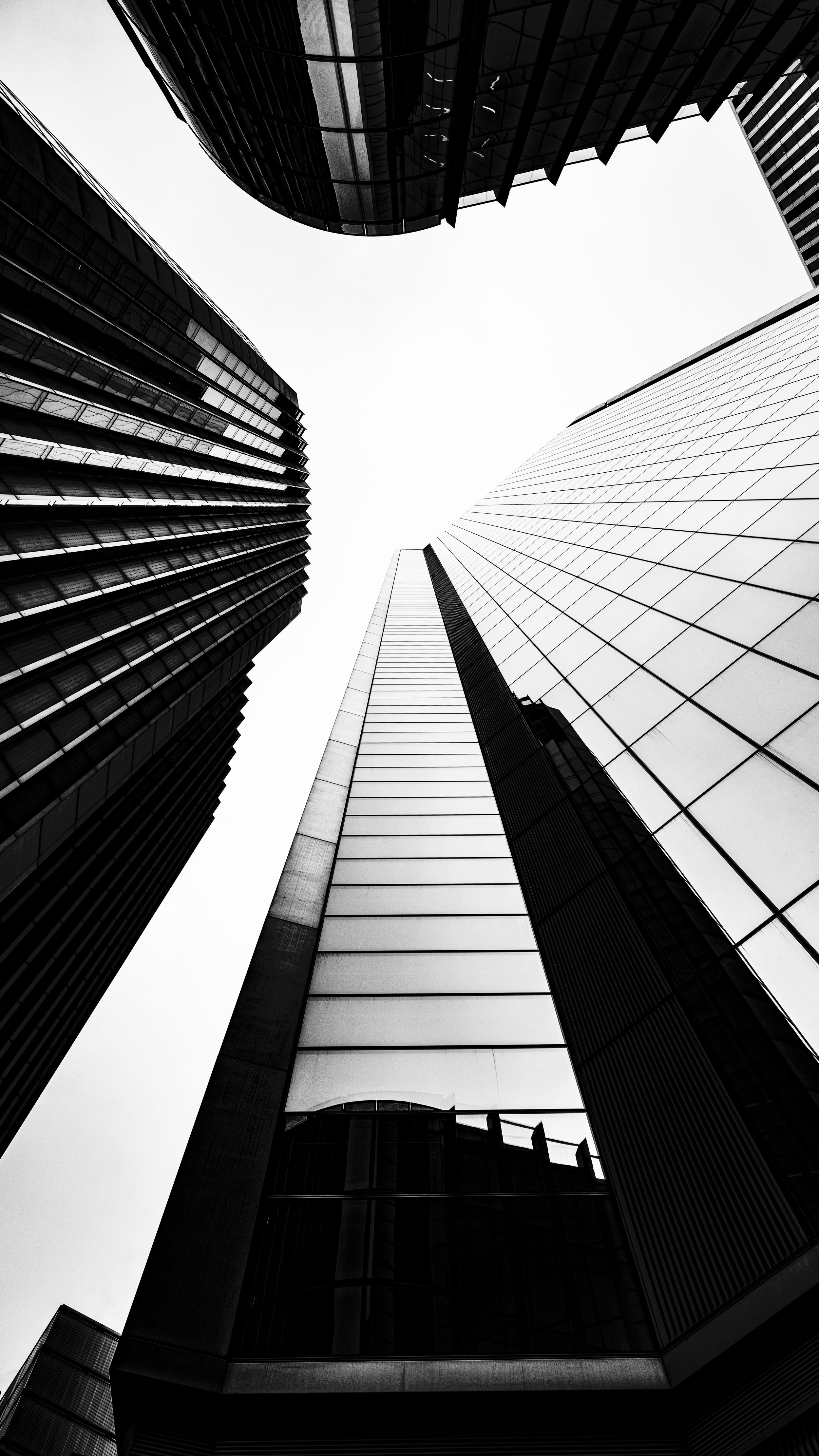 Black and white architectural photo looking up at converging skyscrapers