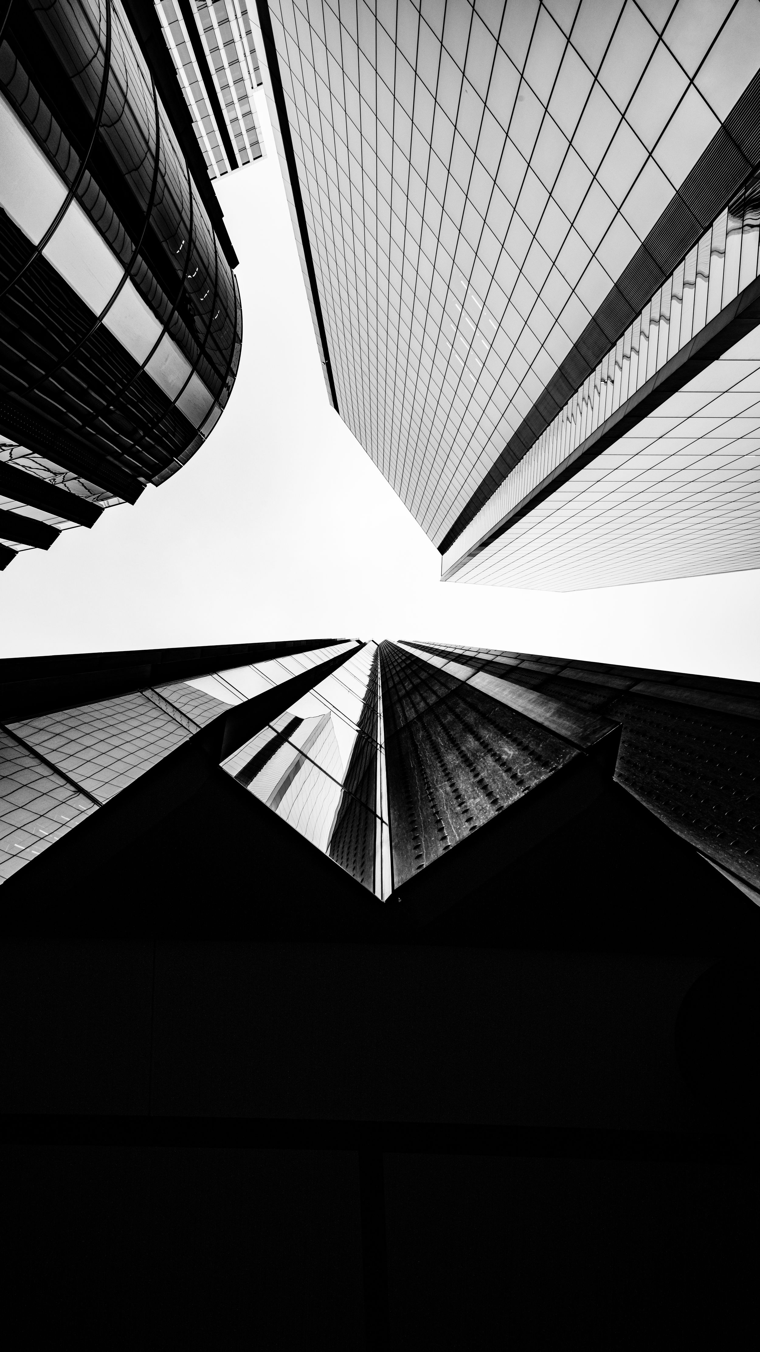 Black and white architectural photo looking up at converging skyscrapers