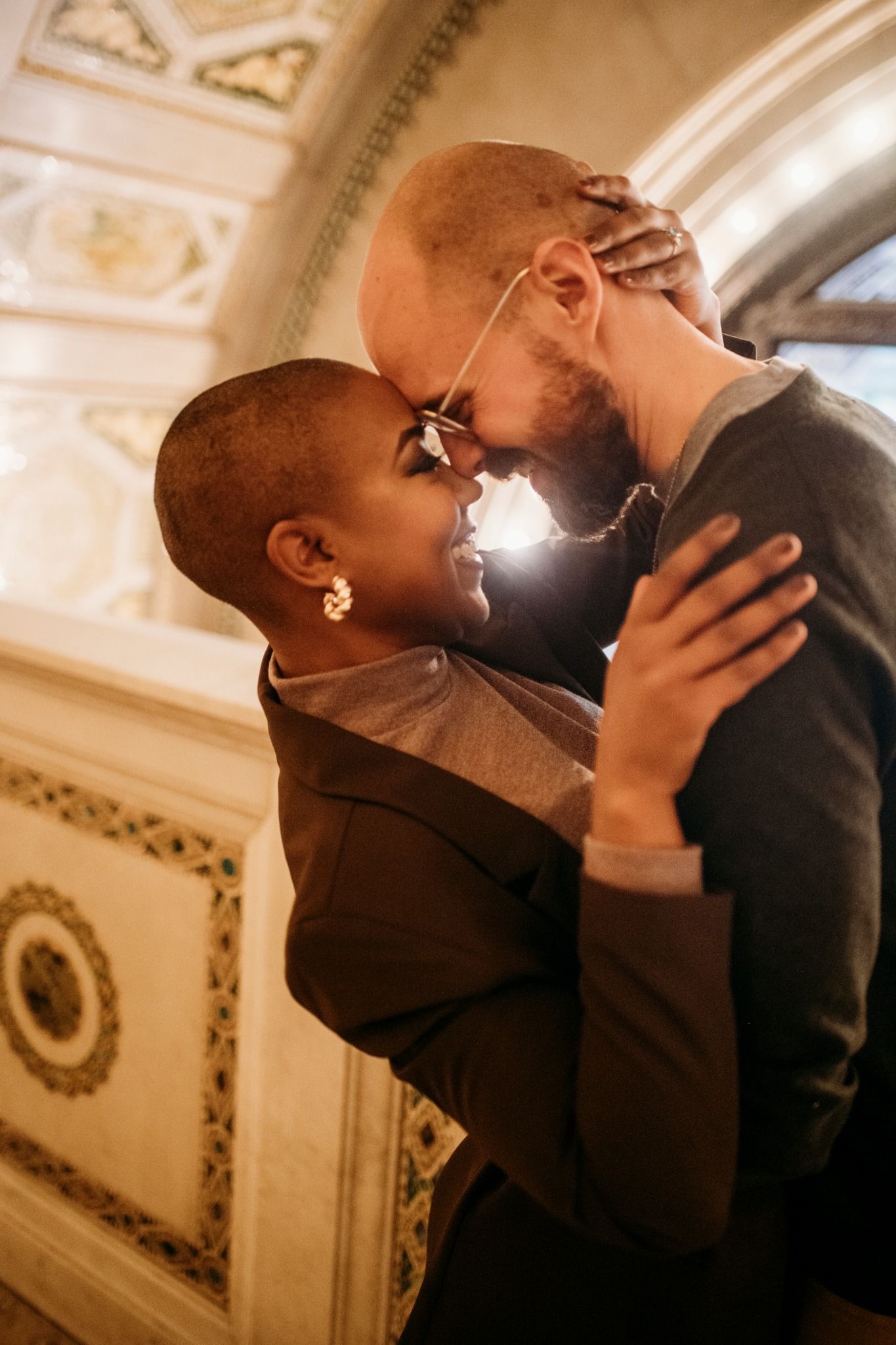 A romantic couple shares an intimate moment, foreheads touching, embracing tenderly in an ornate golden interior.