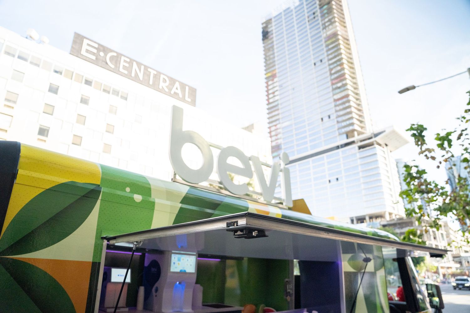 Bevi branded truck parked in urban setting near EX Central building with modern skyscraper in background.