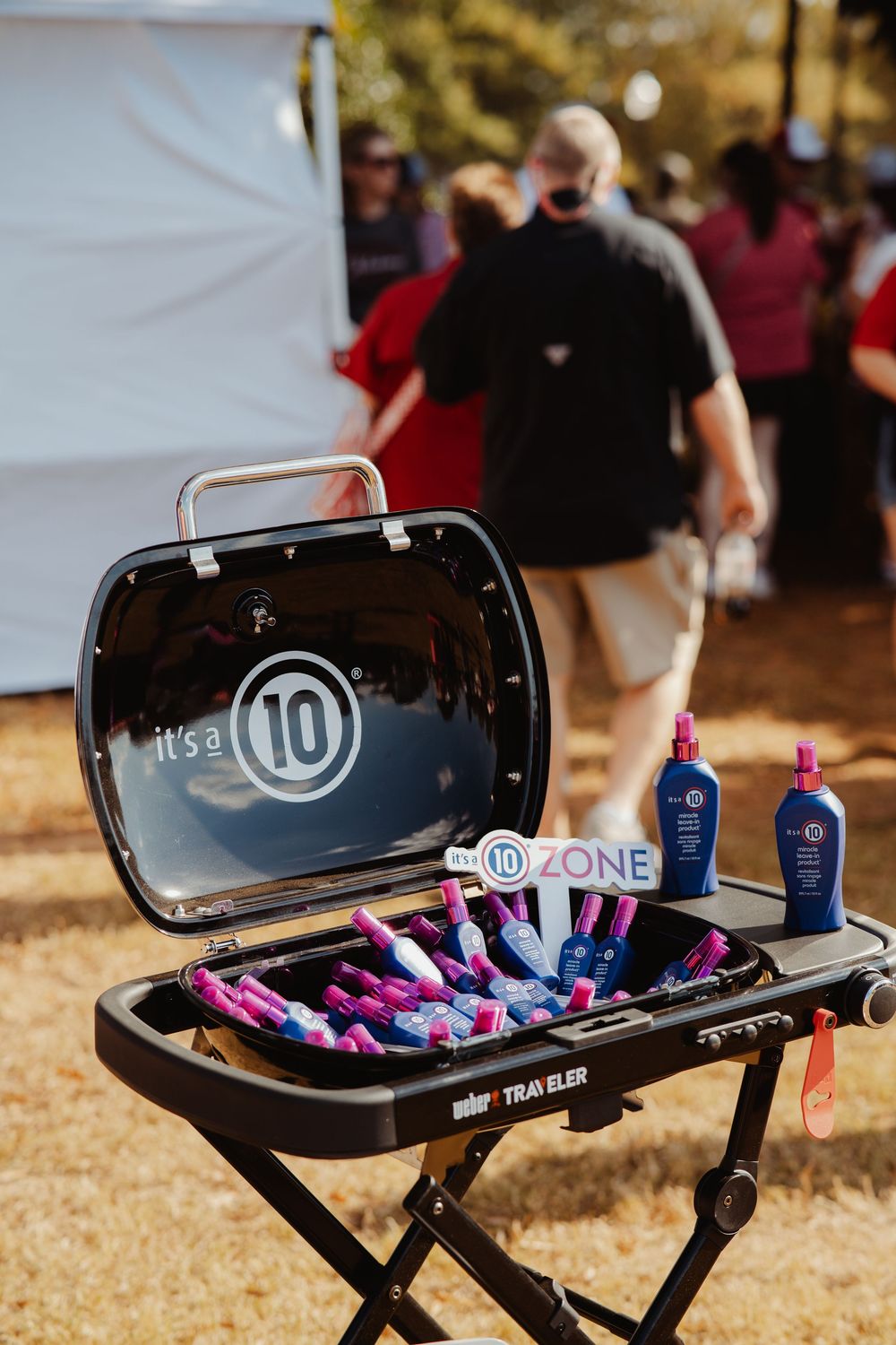 Black Weber grill decorated with pink and blue party supplies and drinks for an outdoor celebration.