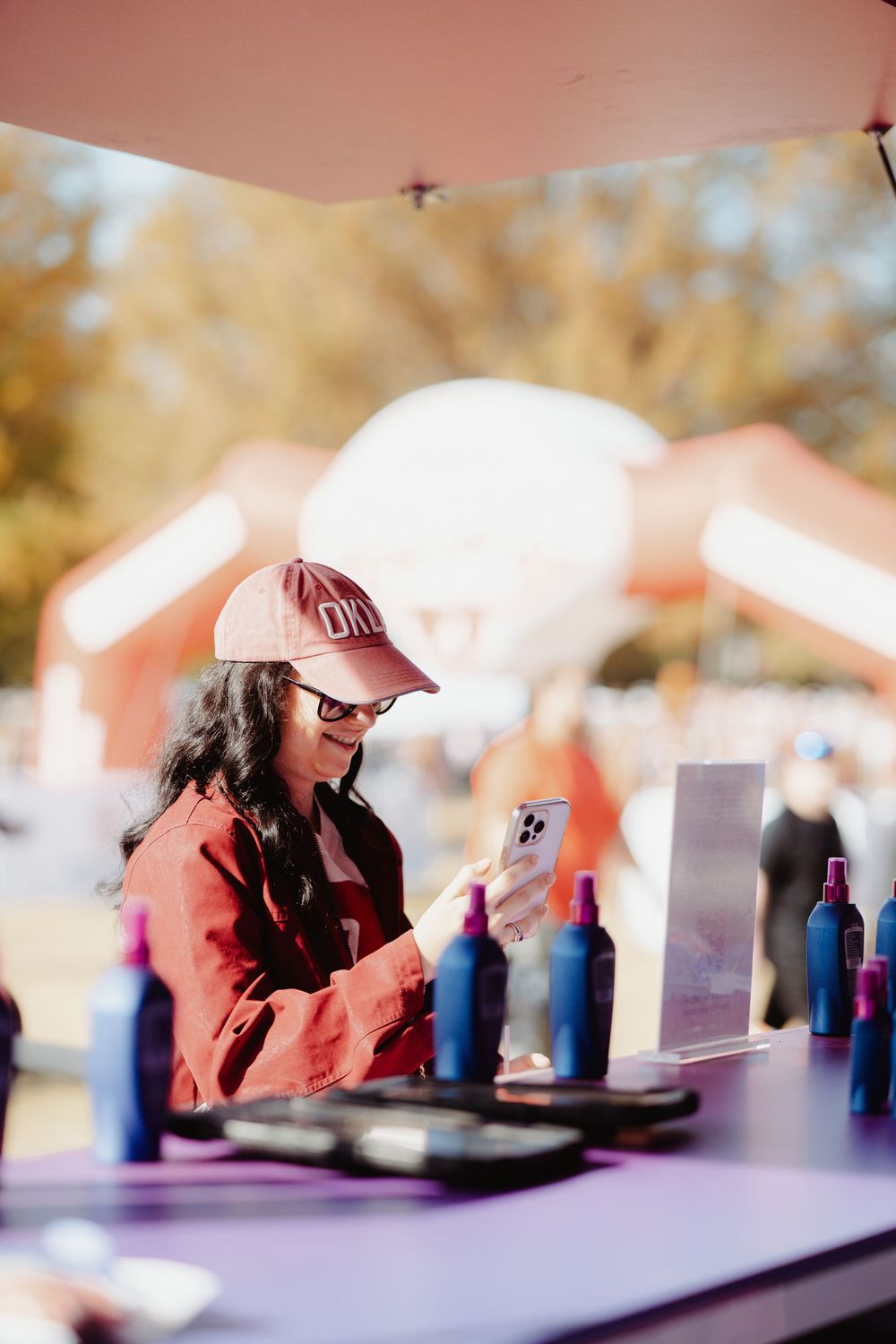 DJ equipment and bottles set up on a table at an outdoor event with a blurred background.