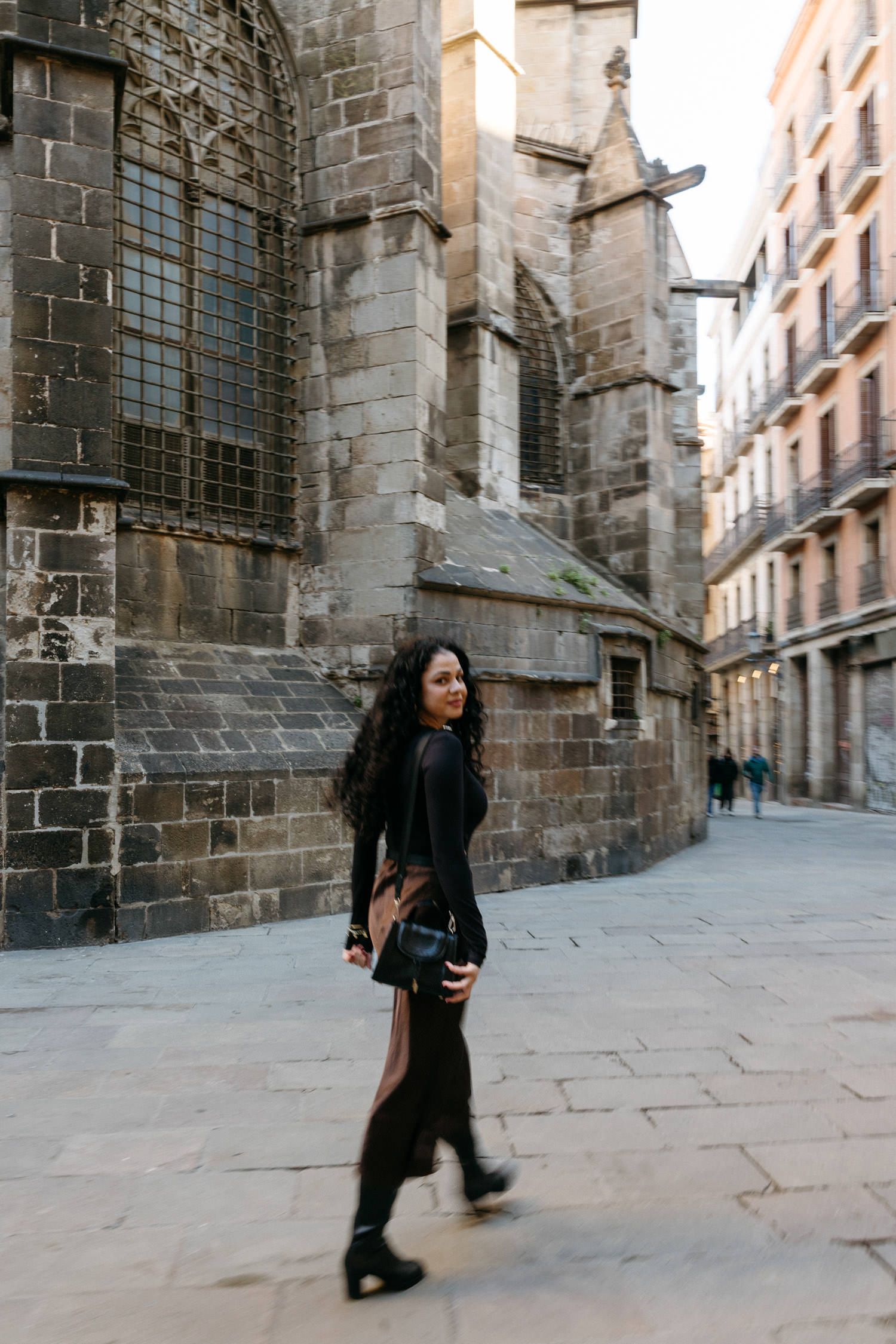 Gothic stone church exterior with narrow cobblestone street and tall windows.
